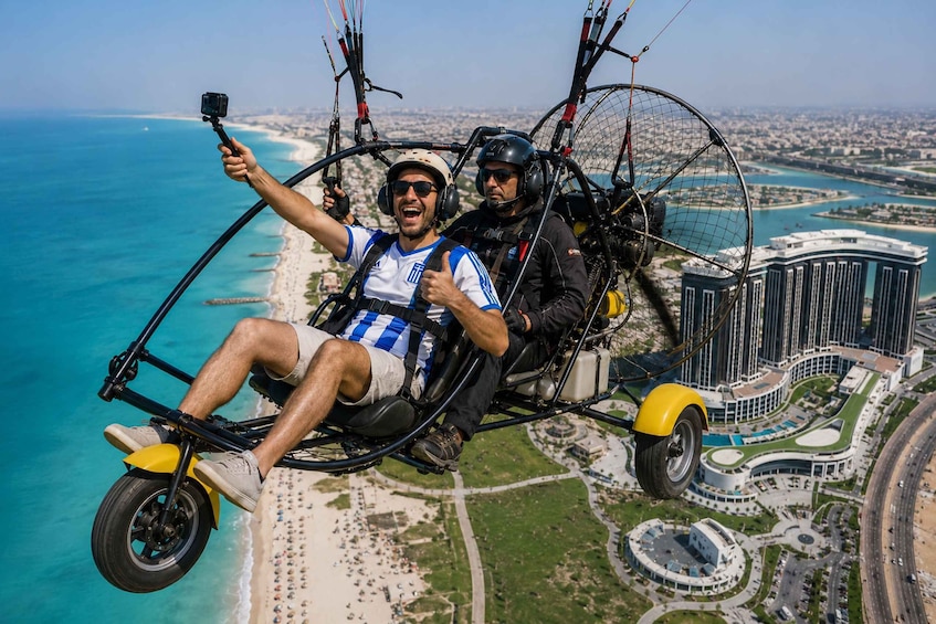 Two people on a tandem paragliding flight over a coastal cityscape. 3