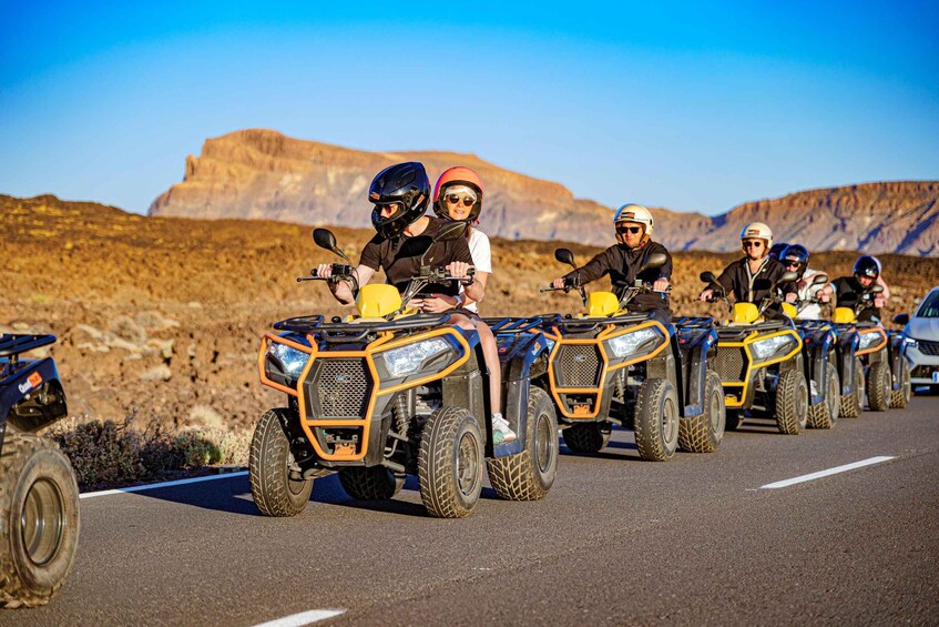 A convoy of ATVs on a paved road with a desert landscape in the background. 2