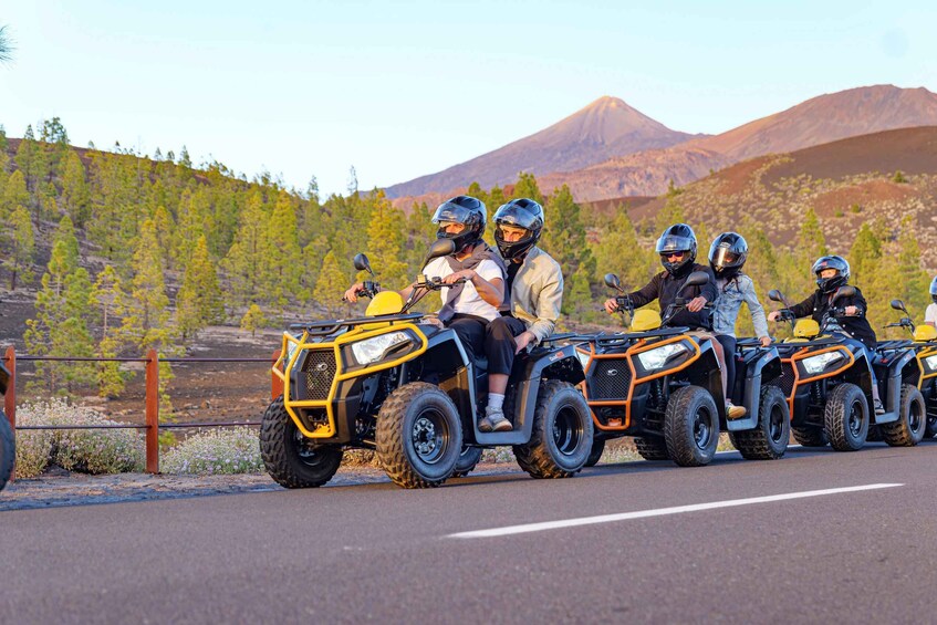A group of people riding ATVs on a road with a mountainous landscape in the background. 3