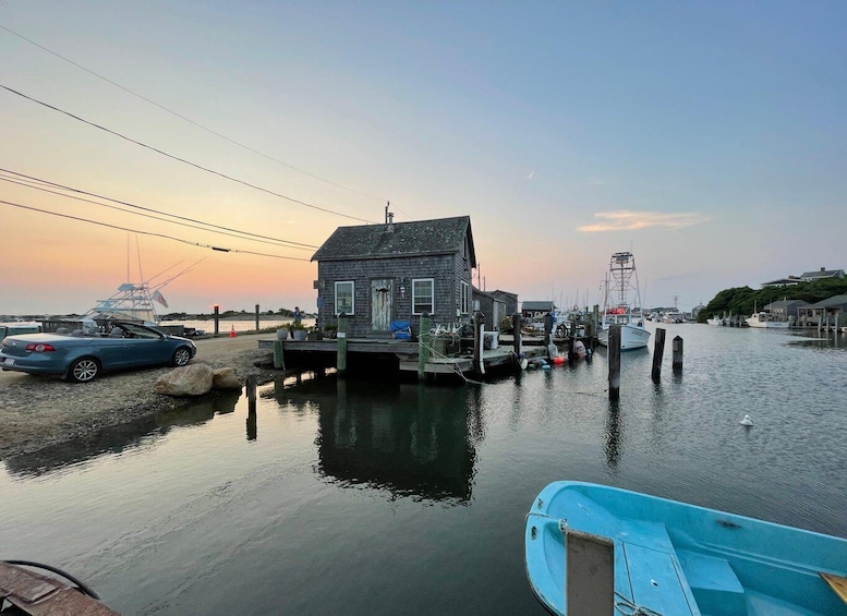 A docked boat, a small house, and a car near a calm waterfront. 3