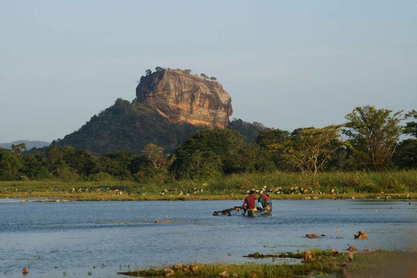 A group of people in a boat on a calm river, with a large rock formation in the background. 3