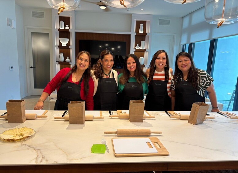 A group of people in a kitchen with marble countertops, wooden cabinets, and hanging pendant lights. 2