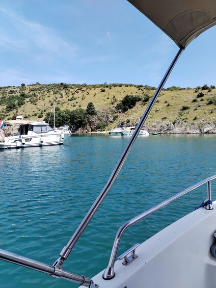 A boat with a metal railing, calm water, and a hilly landscape with sparse vegetation in the background. 5
