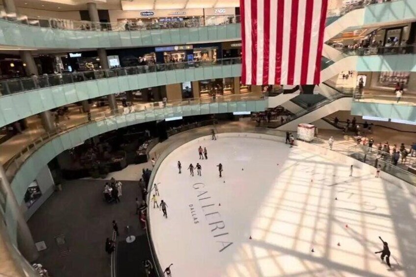 A multi-level shopping mall with a large American flag, a central open space, and multiple floors with shops. 4