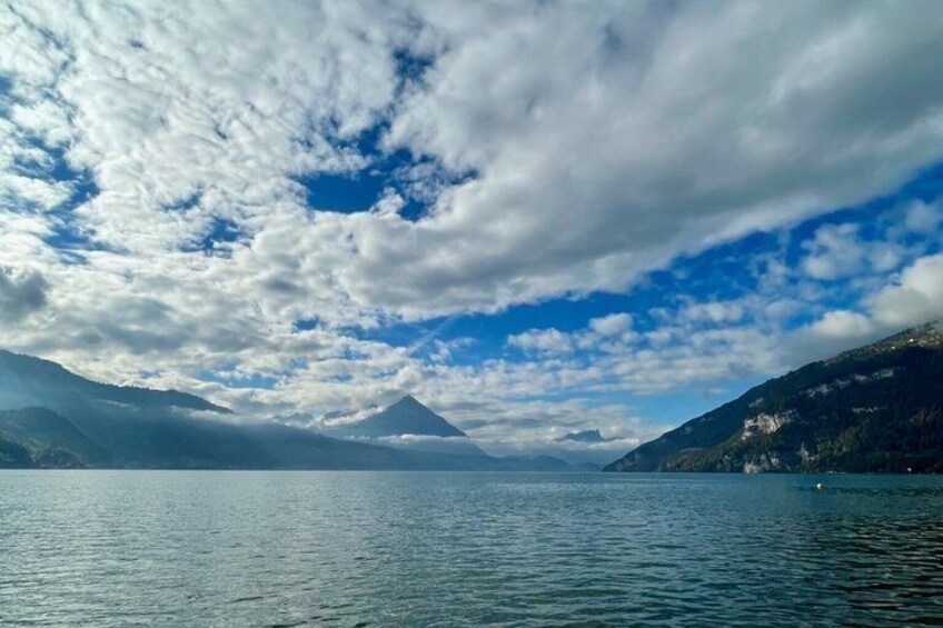 A calm lake with mountains in the background and a partly cloudy sky. 1