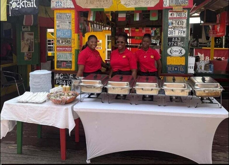 A food stall with a variety of dishes displayed in metal containers, a pizza on a table, and a signboard with various text and numbers. 4