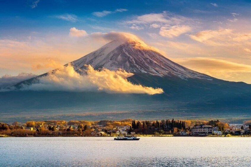 A mountain with a boat on a calm body of water, surrounded by a town. 4