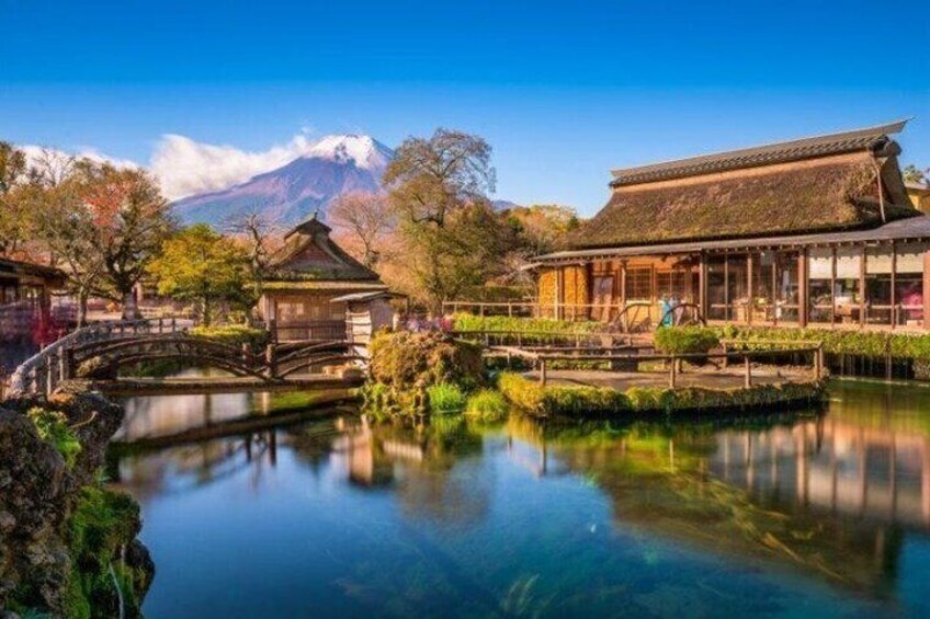 A traditional Japanese garden with a pond, wooden structures, and a mountain in the background. 2