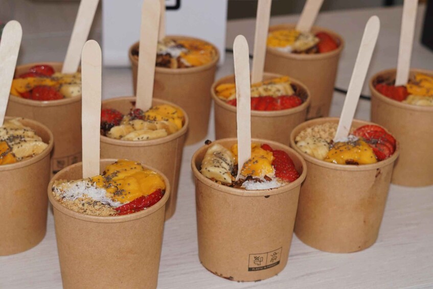Paper cups with wooden straws filled with fruit and granola. 5