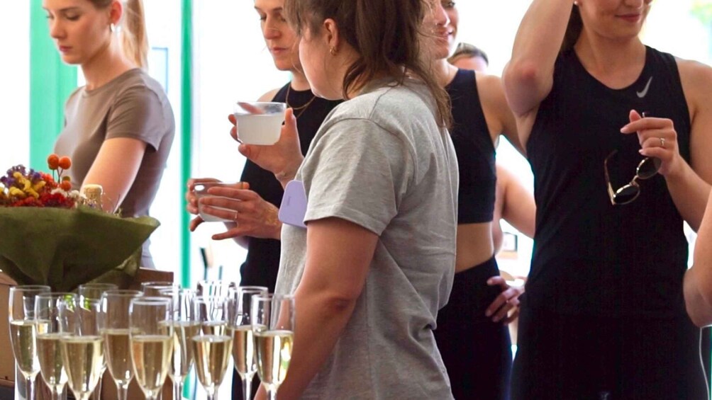 A group of people at a social event with champagne glasses and a floral arrangement. 3