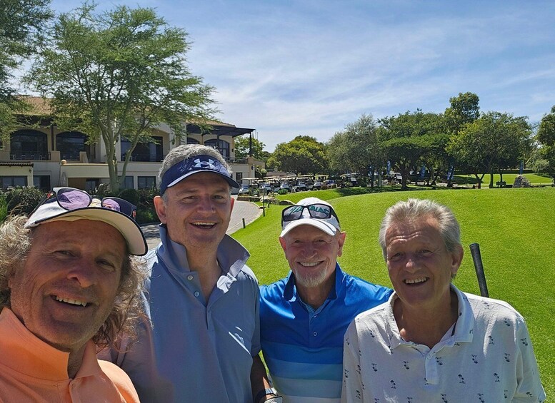 A group of people at a golf course with a building and trees in the background. 1