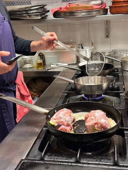 A person cooking meat in a pan on a stove. 4