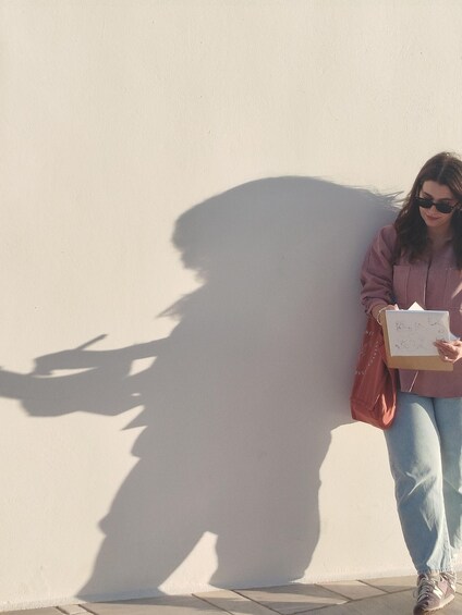 A person walking, holding a book, and casting a shadow on a wall. 5
