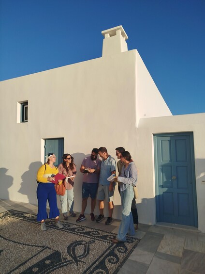 A group of people standing outside a white building with blue doors and windows. 1