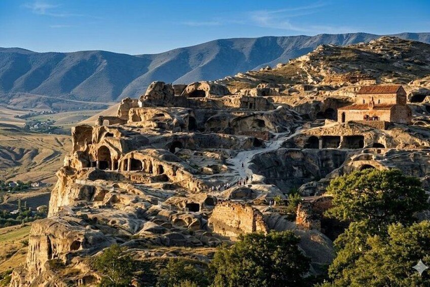 A rugged landscape with ancient ruins and a small building on a hill. 1