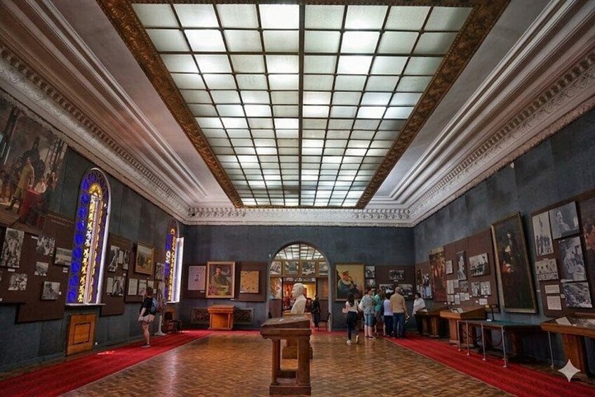 An art gallery with a red carpet, framed artworks, and a central archway. 3