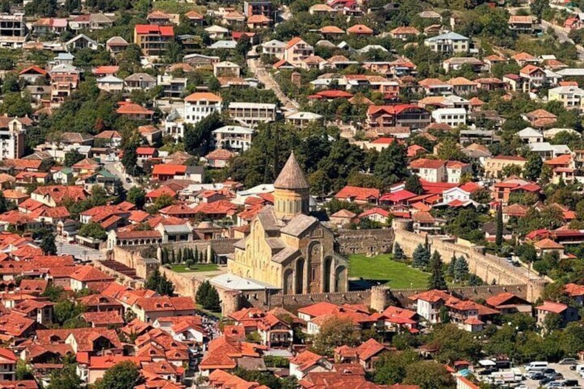 A densely built urban area with a prominent church featuring a tall bell tower and a fortified wall. 5