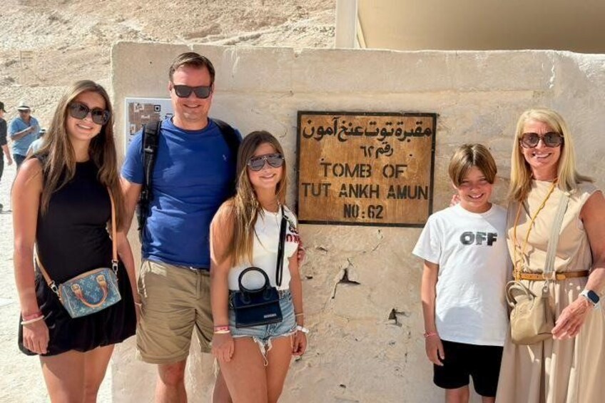 A group of people standing in front of a sign that reads 'TOMB OF TUT ANKH AMUN NO:62'. 5