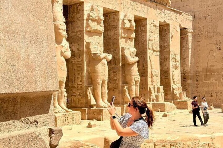 A person taking a photo of ancient Egyptian statues. 1