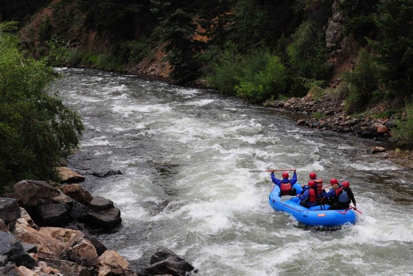 A group of people rafting down a river surrounded by rocks and greenery. 4