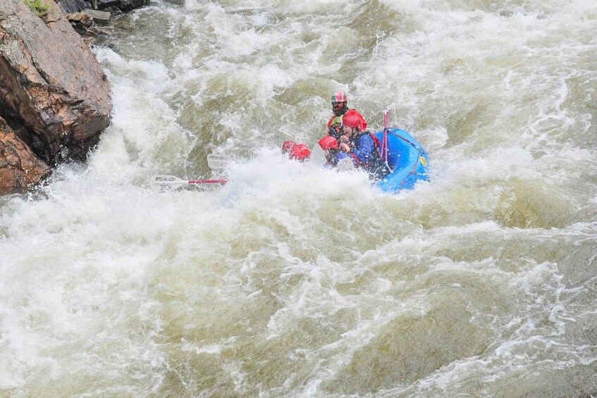 A person in a blue kayak navigating through a turbulent river. 2