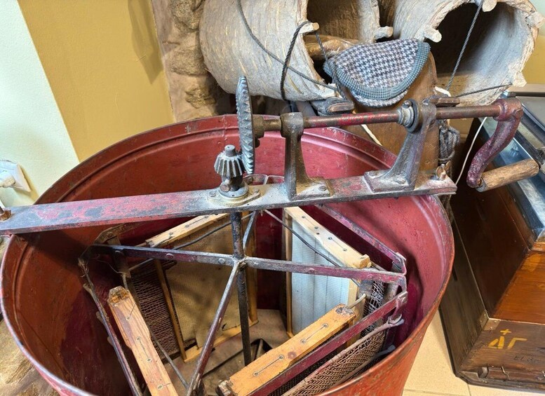 A vintage mechanical device with gears and a wooden handle, possibly a historical tool or machinery. 1