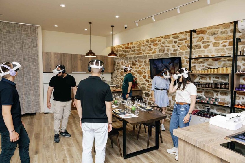 A group of people wearing VR headsets in a modern kitchen with stone walls and a wooden dining table. 2