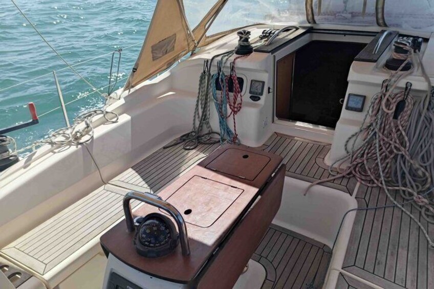 A boat's deck with a teak table, a steering wheel, and various ropes and equipment. 4