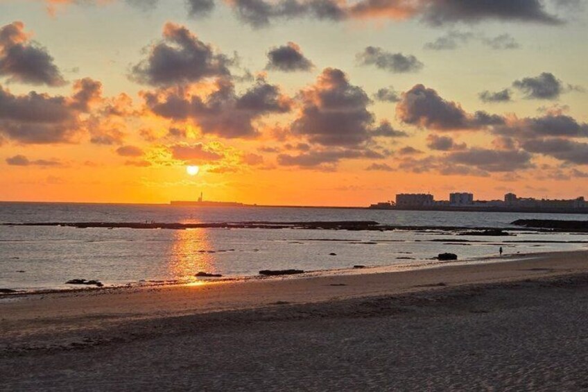 A sunset over a beach with a city skyline in the background. 1