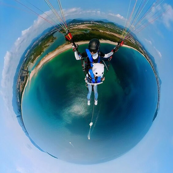 A person paragliding over a coastal area with clear blue waters and a beach. 4