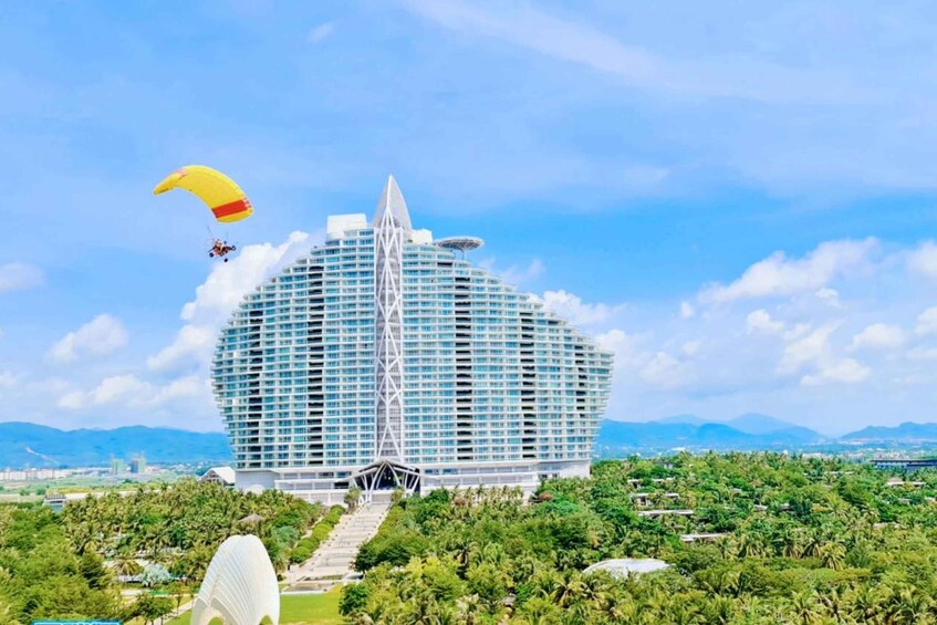 A large, modern building with a unique design, surrounded by lush greenery and a clear blue sky. 3