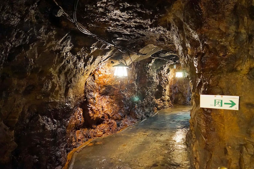 A narrow, illuminated tunnel with a sign indicating an exit to the right. 5
