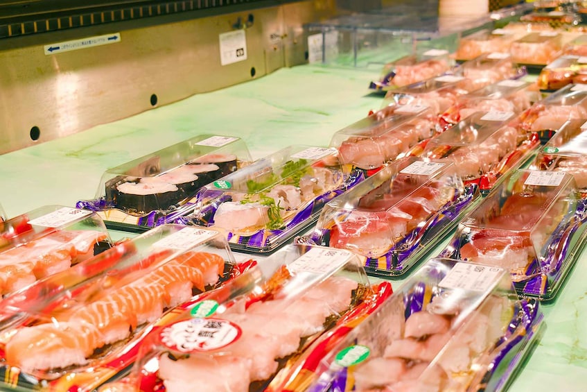 A variety of packaged seafood, including sushi and sashimi, displayed in a refrigerated section of a market. 4