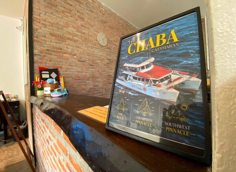 A framed poster of a boat named 'The Chaba' with text 'Catamaran' and 'Southwest Pinnacle' on a wooden counter. 2