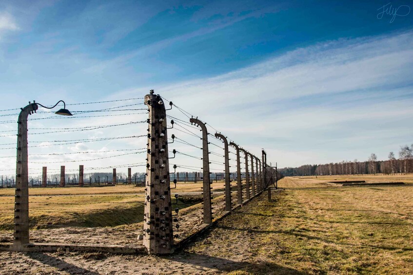 A barbed wire fence with surveillance cameras and street lamps. 1