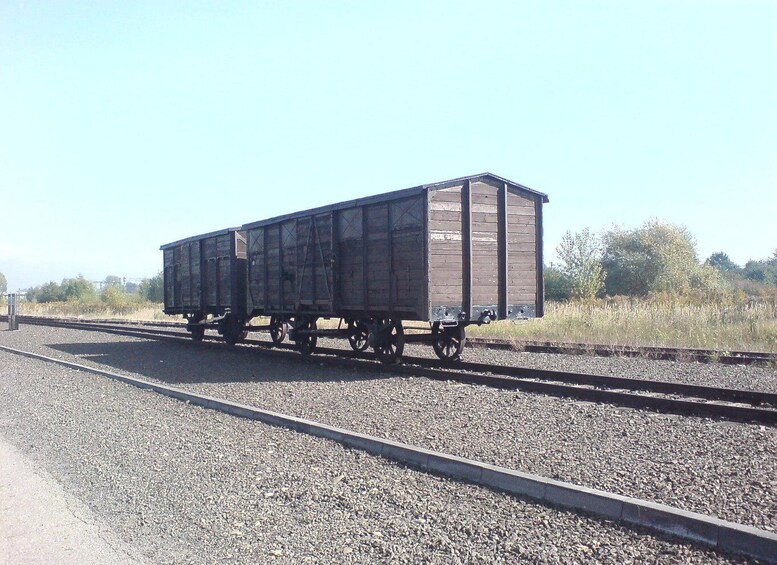 A train car on tracks with gravel and vegetation in the background. 3