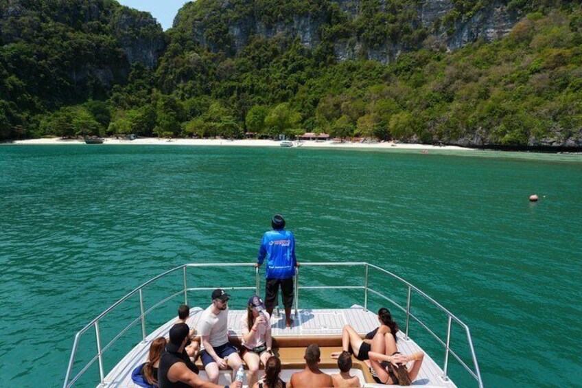 A boat with people on a turquoise sea, cliffs in the background, and a sandy beach. 5