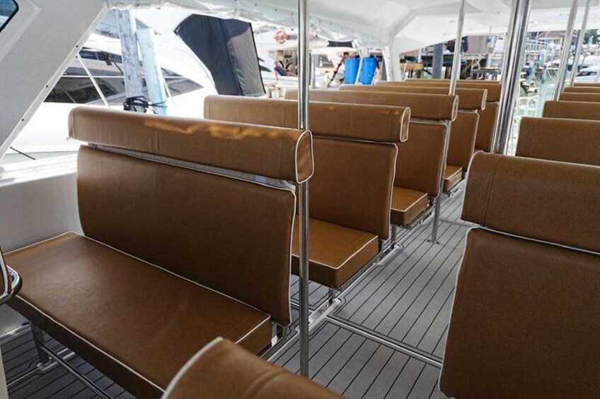 A boat deck with rows of brown cushioned seats and metal railings. 4