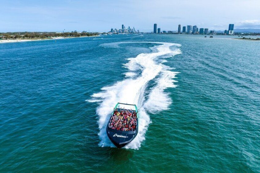 A jet ski creating a wake in turquoise water with a city skyline in the background. 2