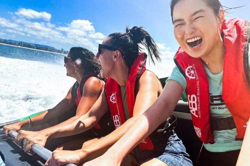 Three people on a jet ski wearing red life vests with 'ABS' logos. 4