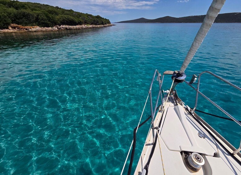 A boat on clear turquoise water with a rocky shoreline and hills in the background. 5