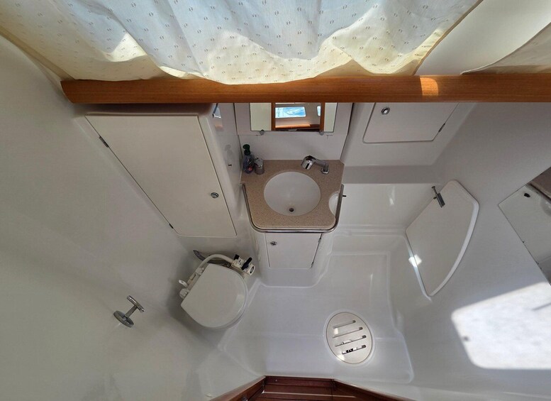 A compact bathroom with a toilet, sink, and shower. 2