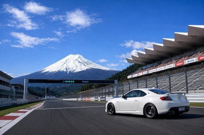 A white sports car on a race track with a mountain in the background. 1