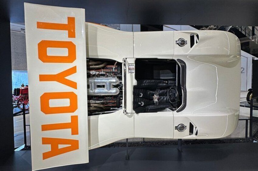 A white Toyota vehicle with its hood open, displaying the engine. 2