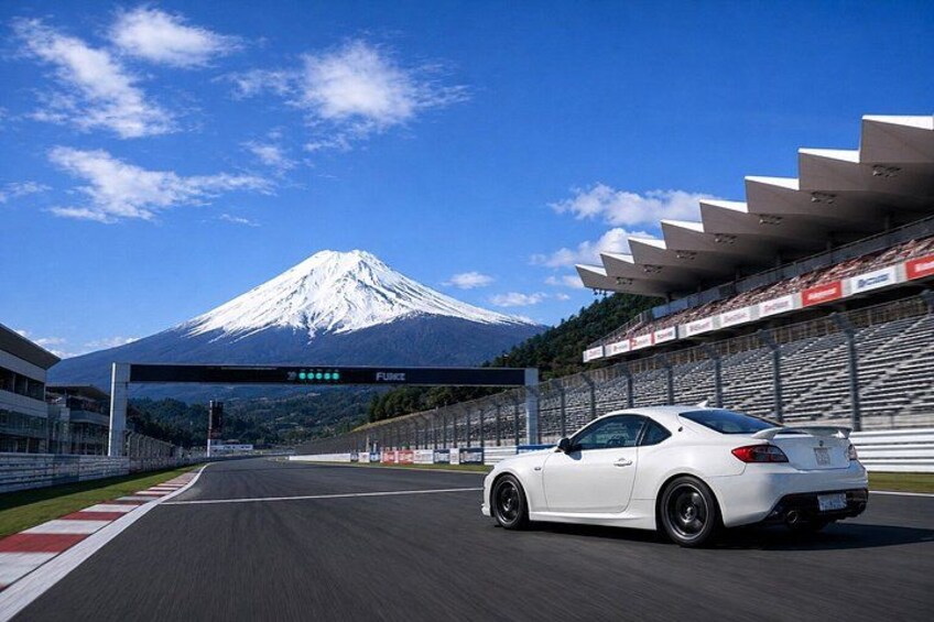 A white sports car on a race track with a mountain in the background. 1