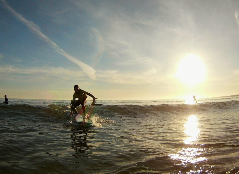 A surfer riding a wave with the sun setting in the background. 1
