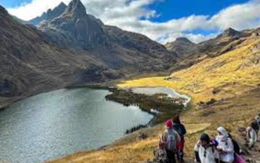A mountainous landscape with a lake and hikers in the foreground. 2