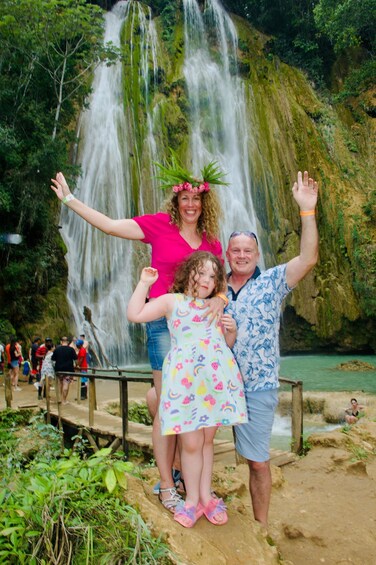 A family posing in front of a waterfall with lush greenery in the background. 5