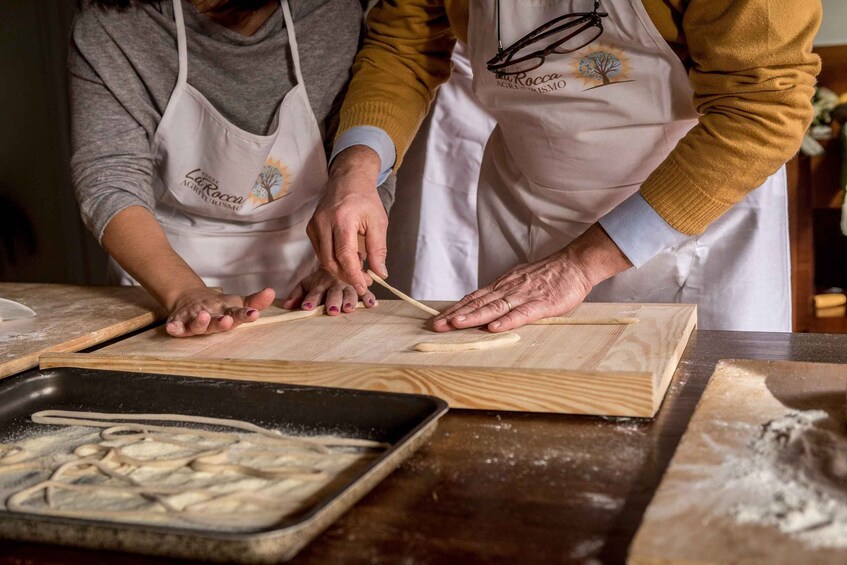 Two people wearing aprons, working with dough on wooden boards. 1
