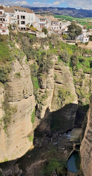 A canyon with a river, rocky cliffs, and white buildings in the background. 5